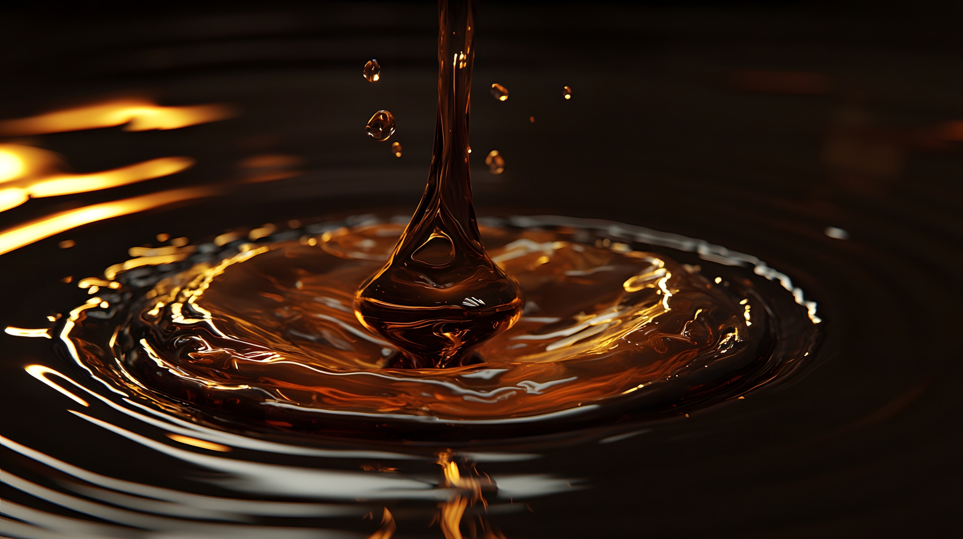 Close-up of dark amber liquid creating ripples and droplets as it pours into a pool.